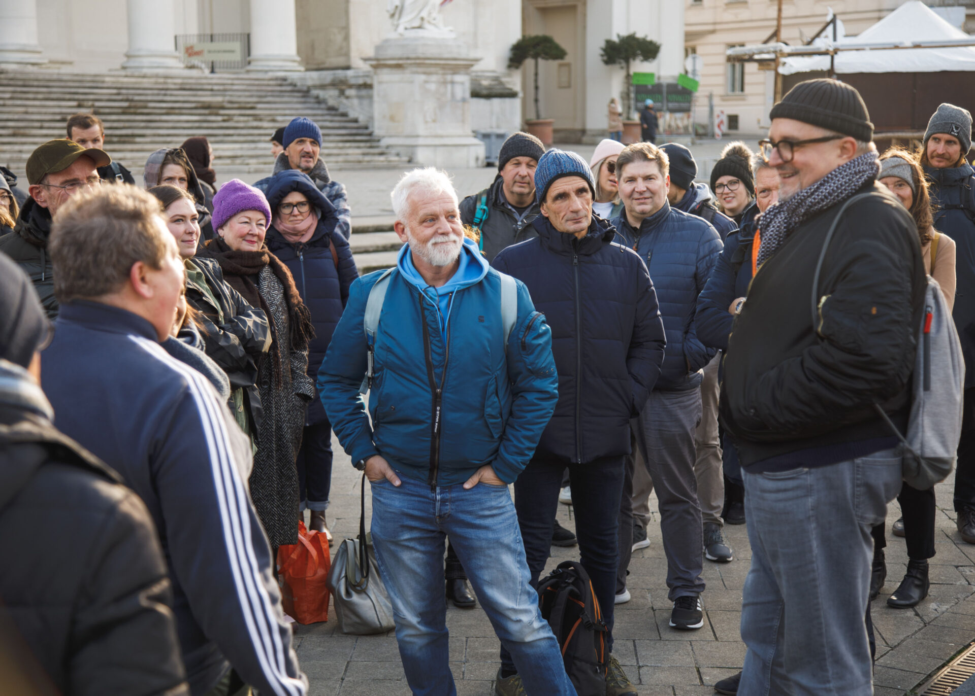 Group of people gathered outdoors, listening attentively to a speaker during a discussion.