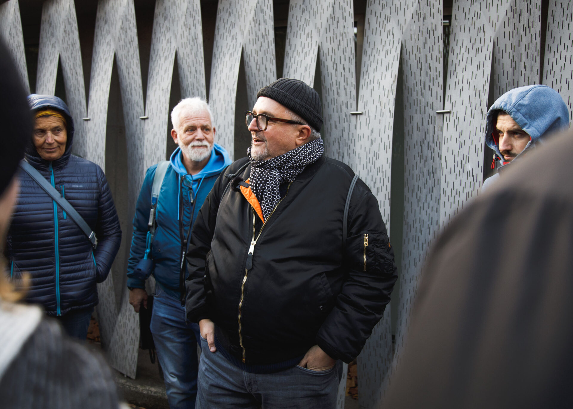 Group discussion led by a speaker in a black jacket and beanie outdoors.