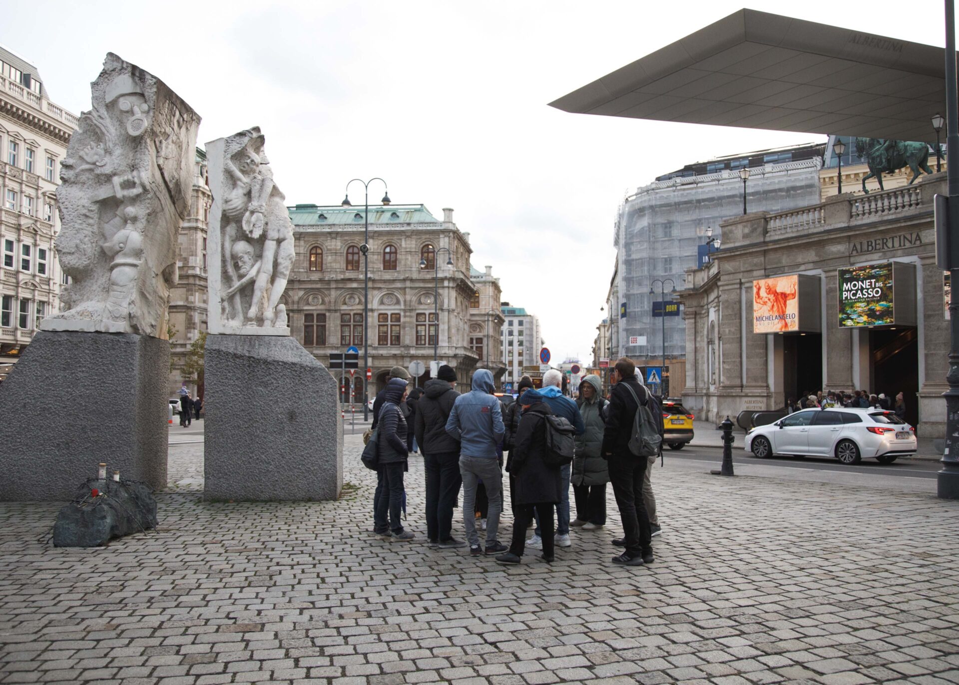 Group of people gathered near sculptures and the Albertina museum in Vienna.