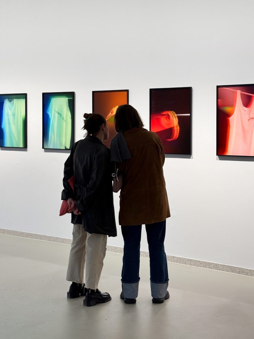 Zwei Personen betrachten Kunstwerke mit leuchtenden Farben in einer Galerie.